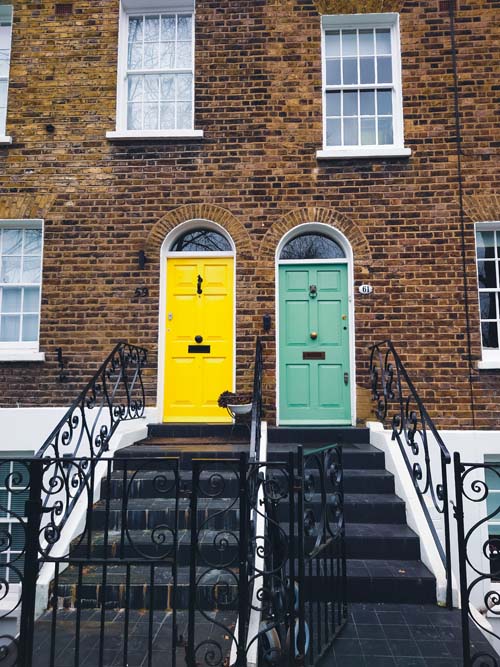 The colorful front doors of traditional brick houses with wrought iron railings